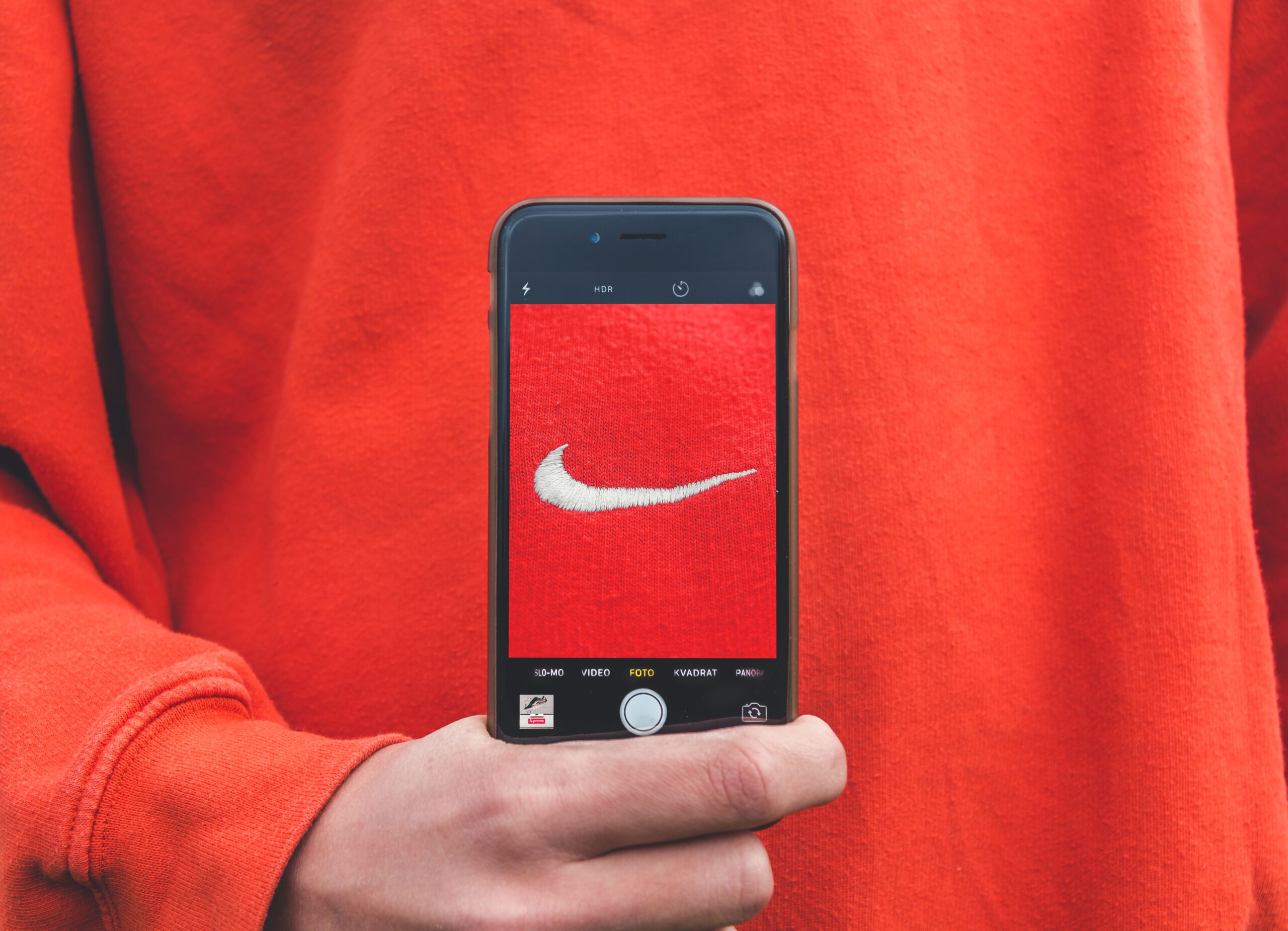 Person holding a smartphone with the Nike logo of their sweater visible on the screen