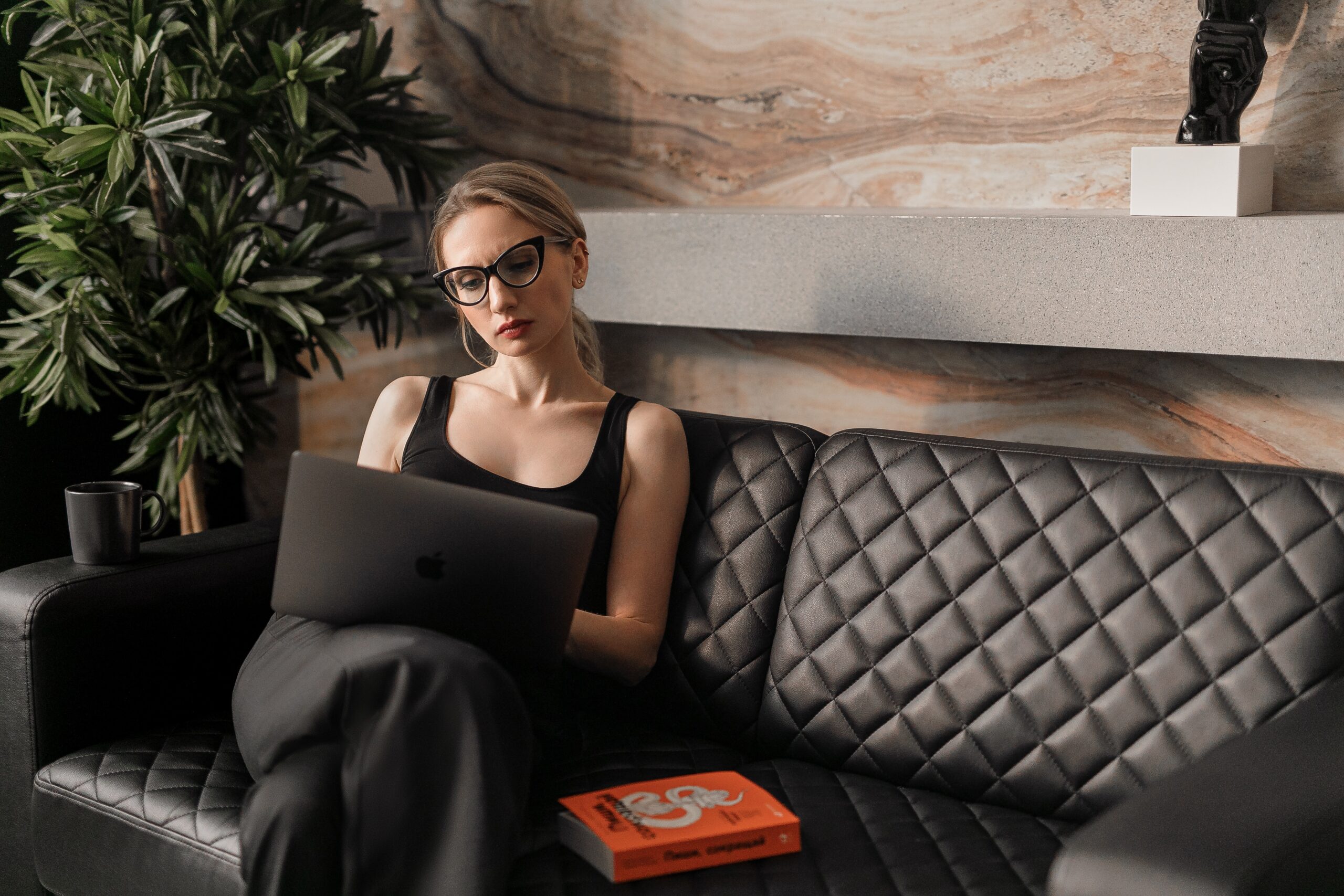 Young woman working on a leather couch in a creative office space