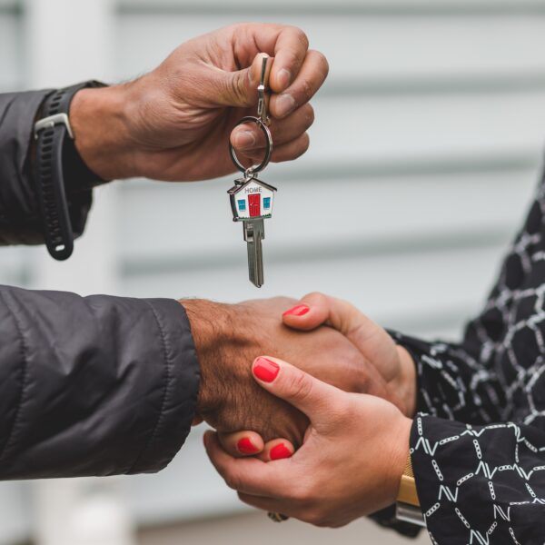 Two people shaking hands whilst presenting a house key