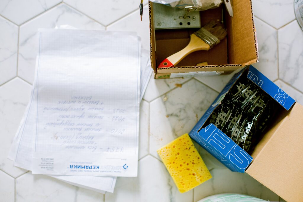 Papers, sponge and boxes of decorating supplies on a tiled floor