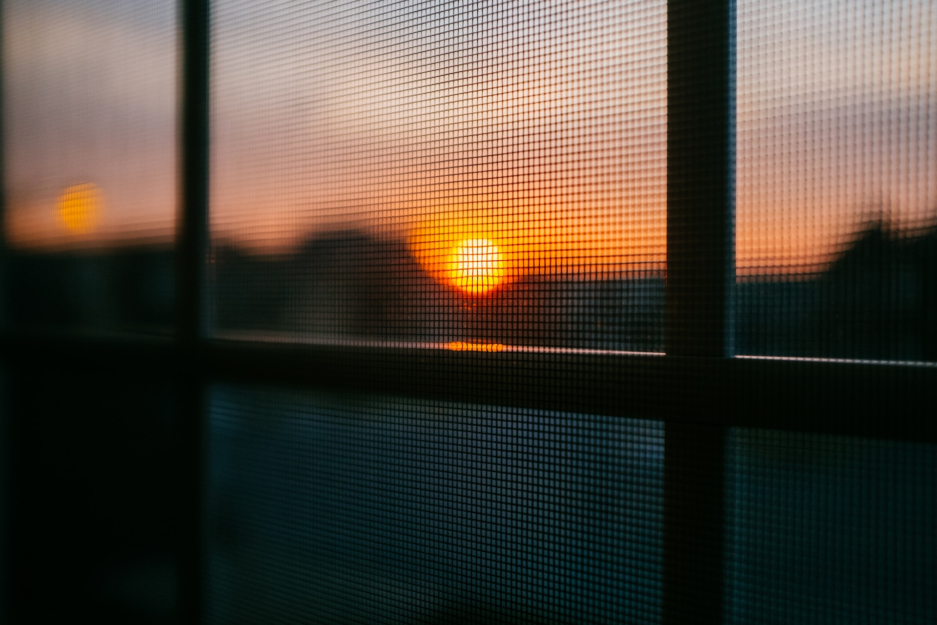 Sunrise as seen though a window with a screen