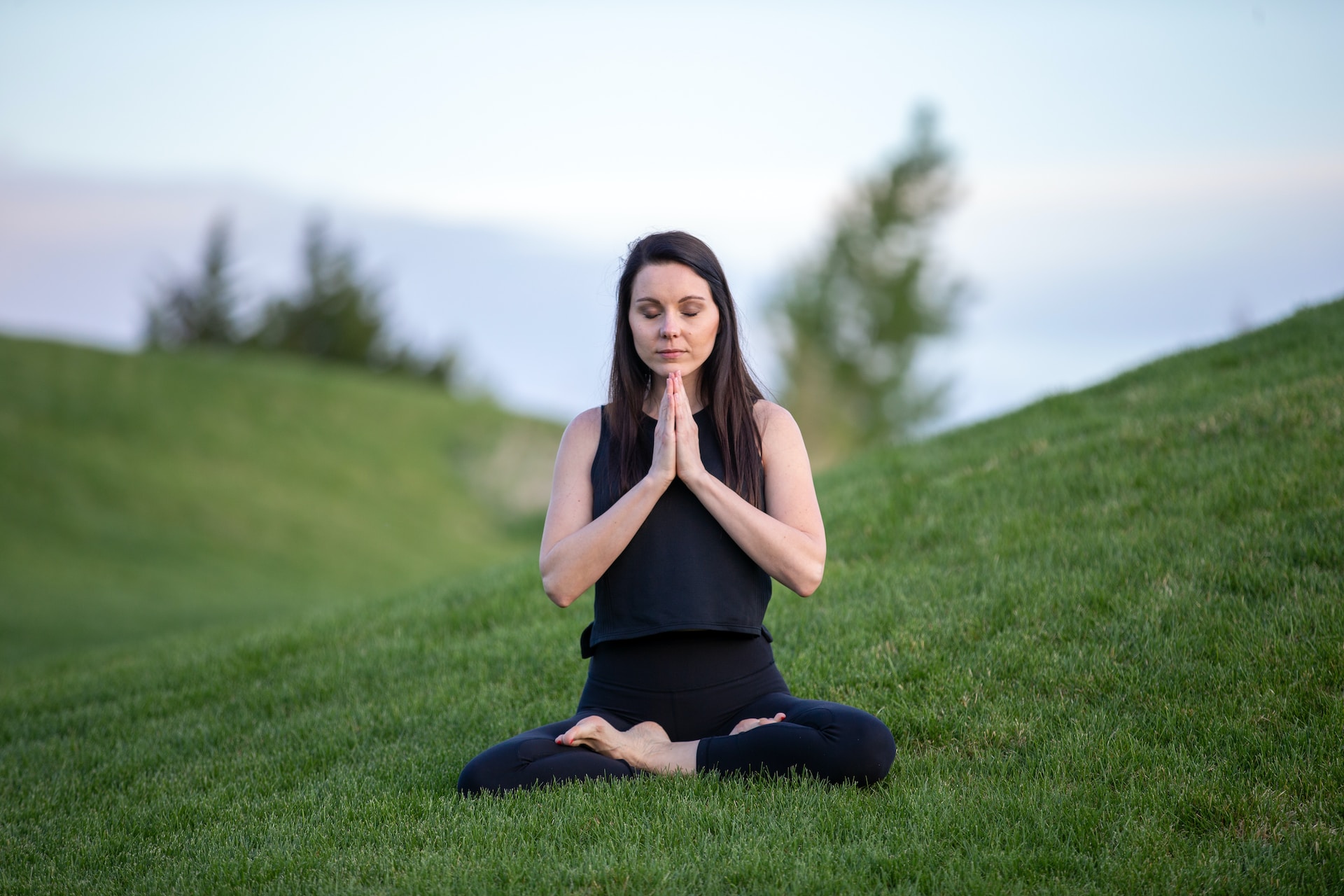 Woman sitting on grass and meditating