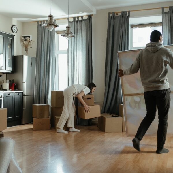 Man carrying a wrapped up painting and a woman lifting a box