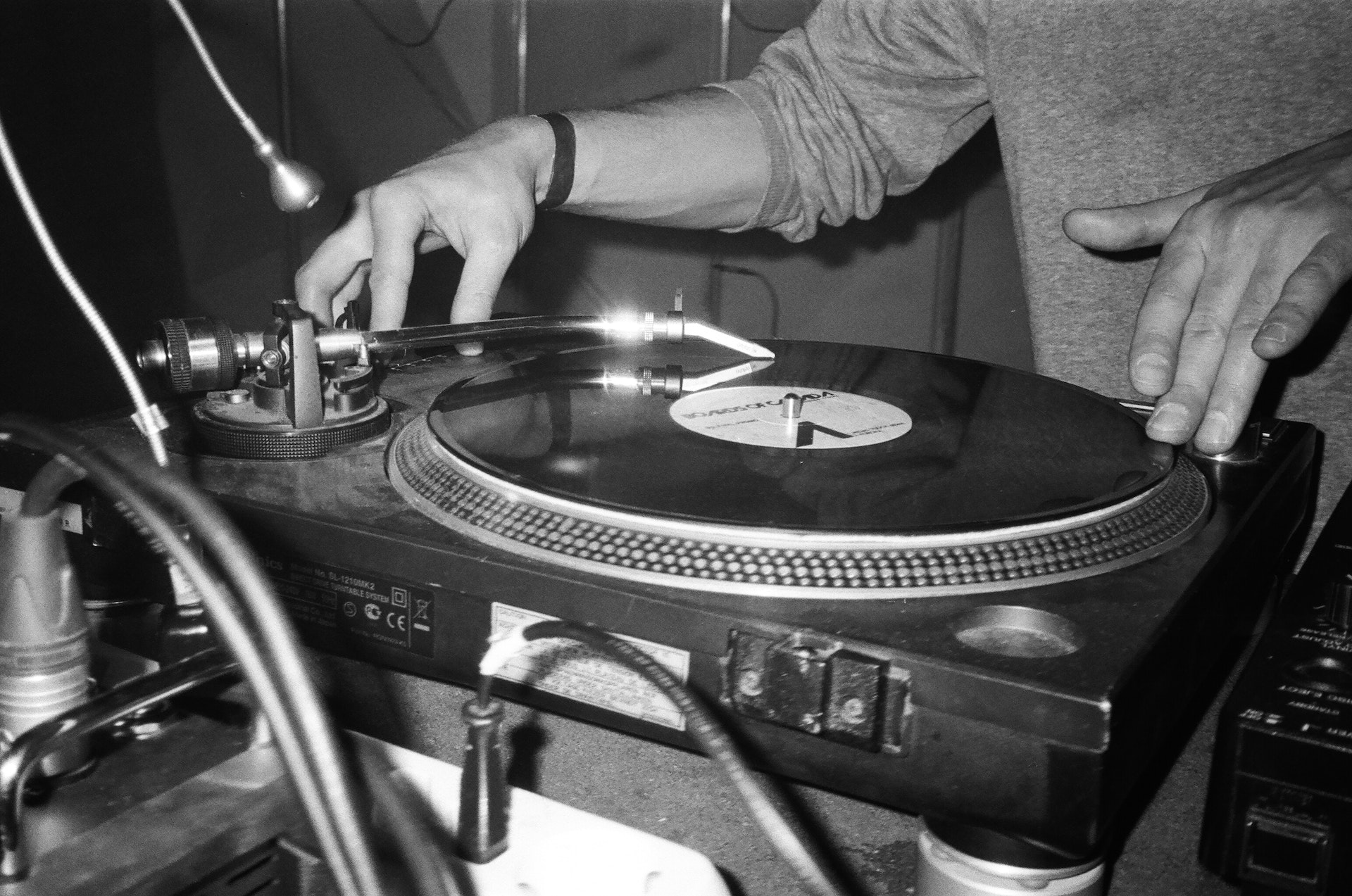 Grayscale photography of person playing a turntable