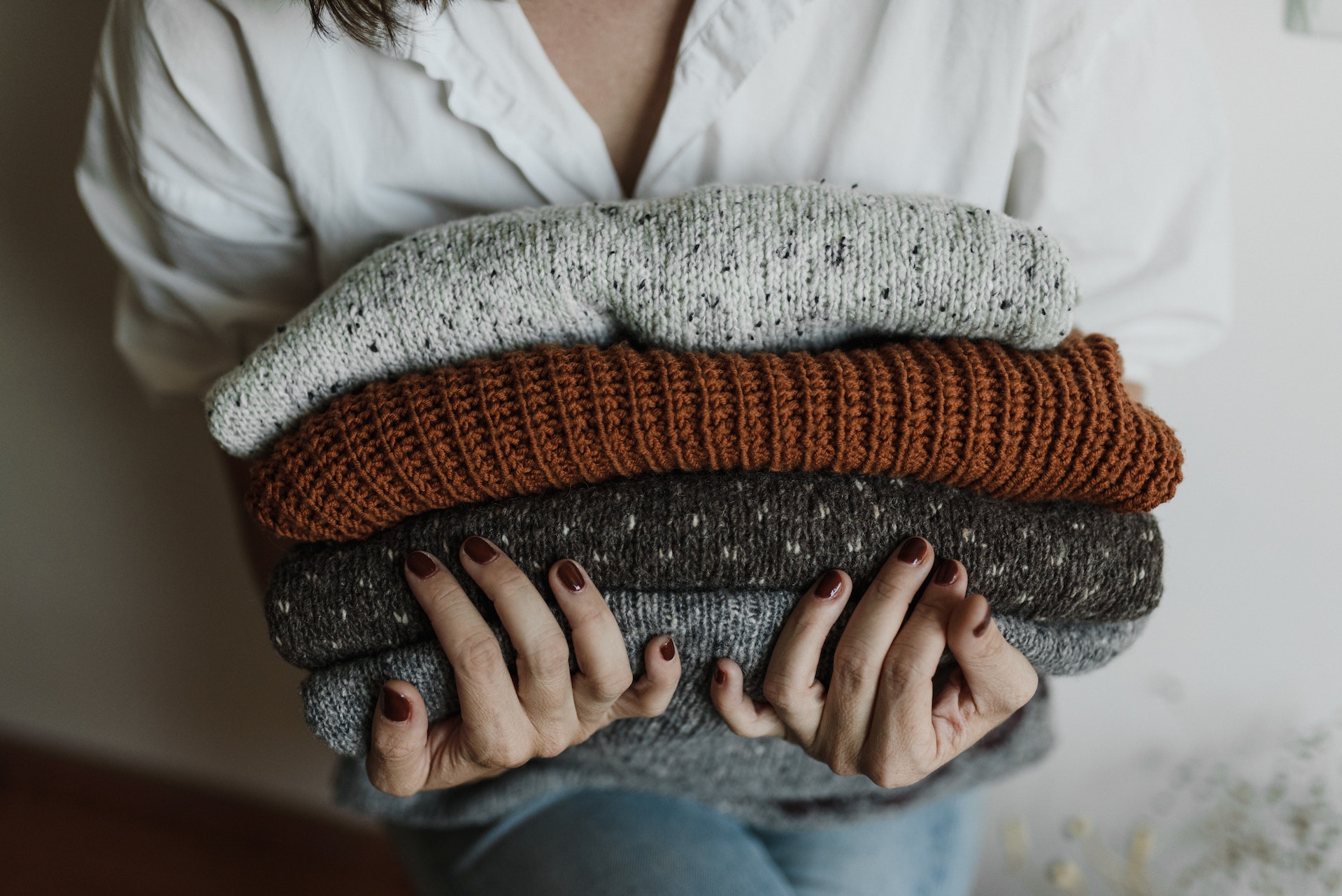 Woman holding a pile of jumpers