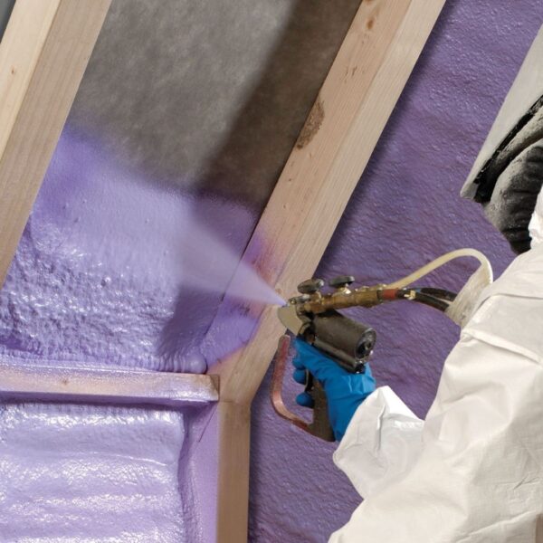 Person in a white suit and mask installing spray foam insulation