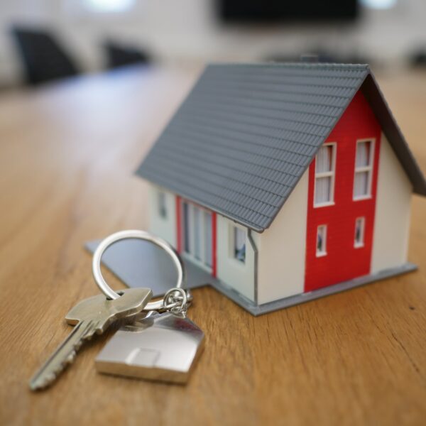 White and red wooden house miniature on brown table with a key