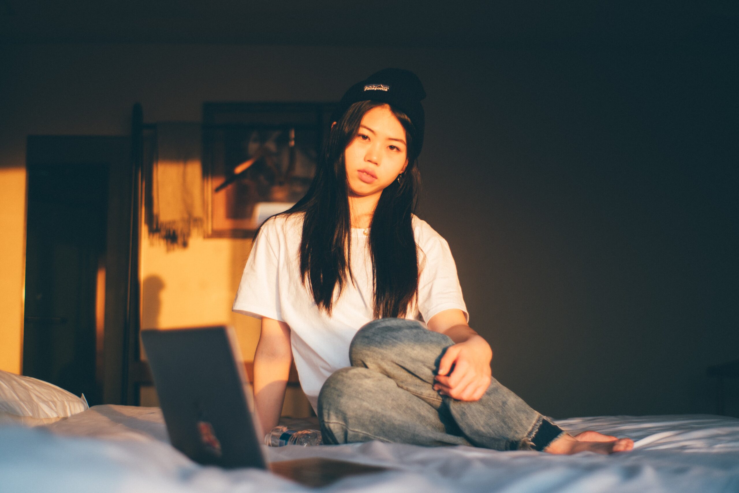 Teenage girl sitting on bed with a laptop
