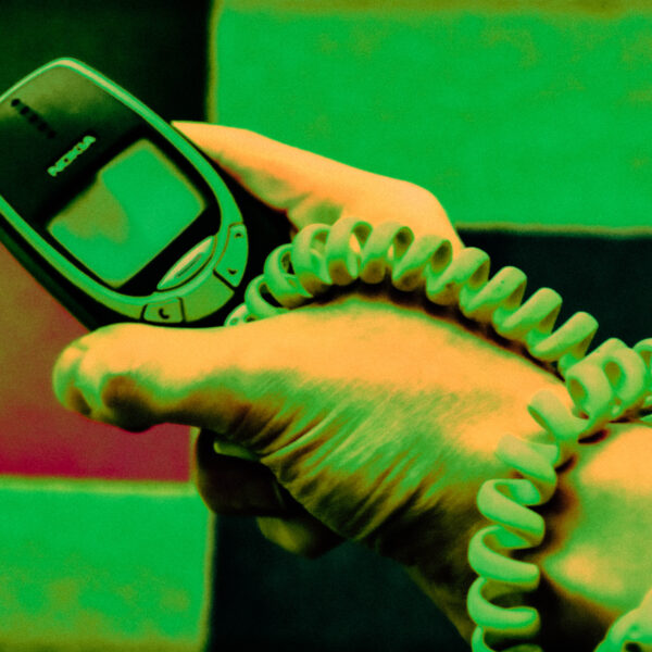 Hand holding a Nokia 3310 with a telephone cable wrapped around wrist