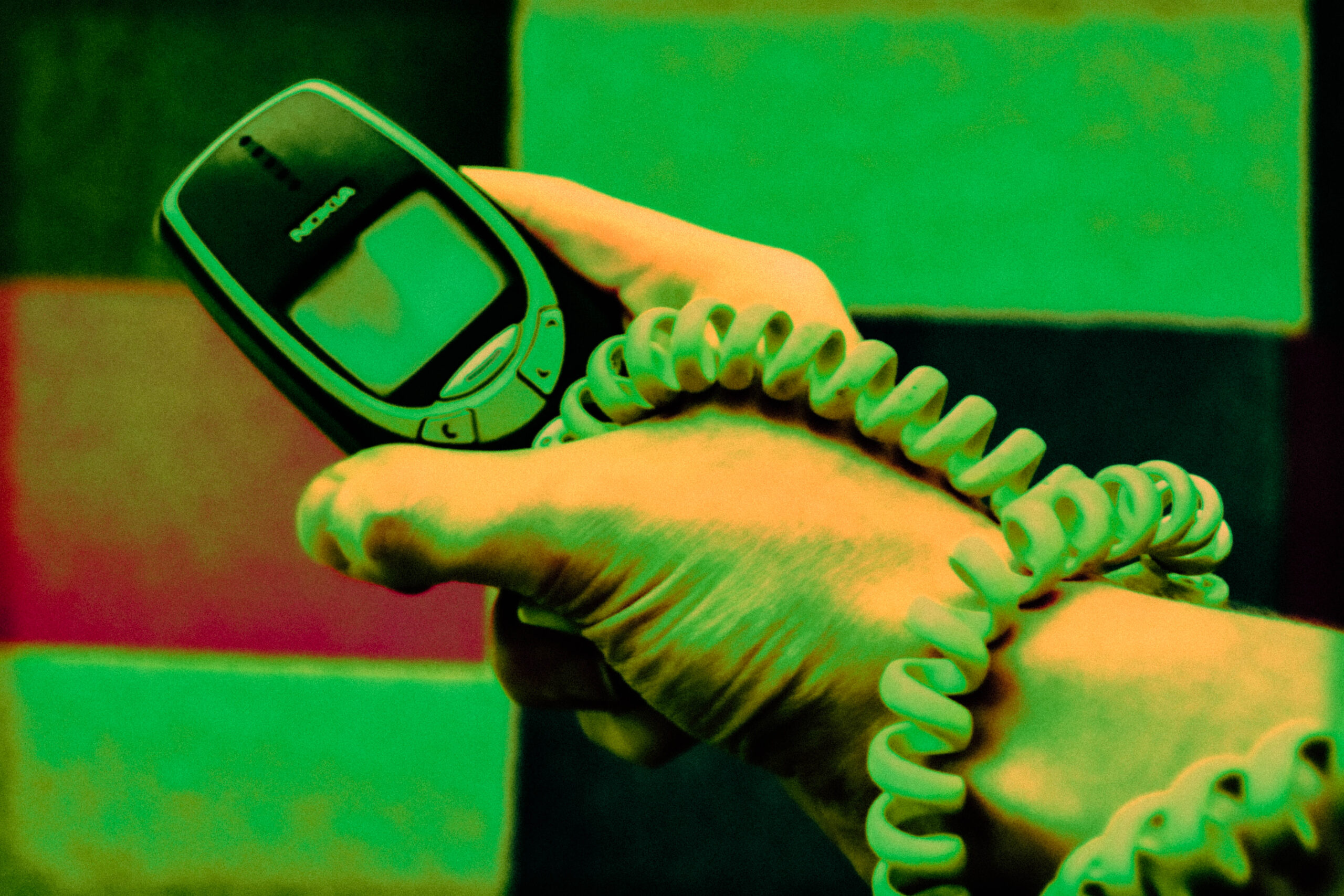 Hand holding a Nokia 3310 with a telephone cable wrapped around wrist