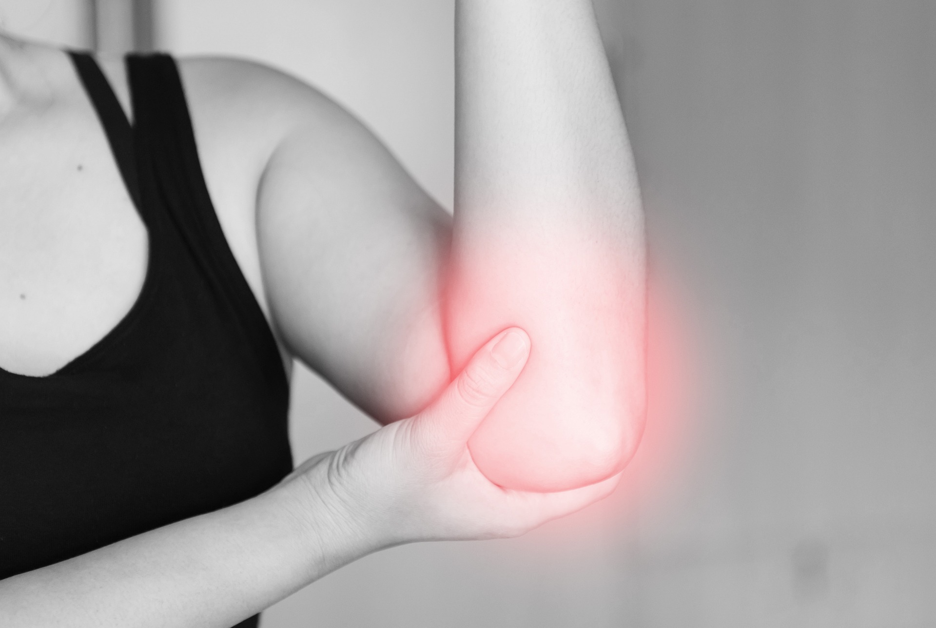 Grayscale photo of a person with injured elbow. The elbow looks like it has a faint red glow.