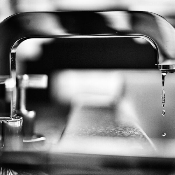 Greyscale photo of a leaky faucet