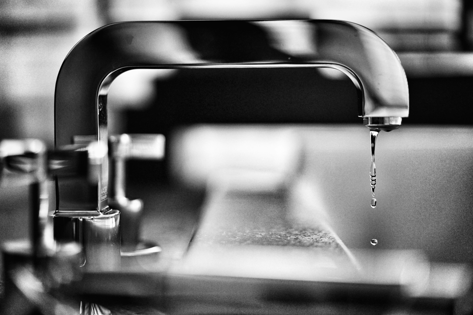 Greyscale photo of a leaky faucet