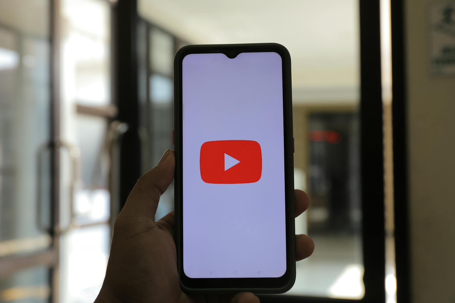 Person holding a smartphone with the YouTube logo on the screen