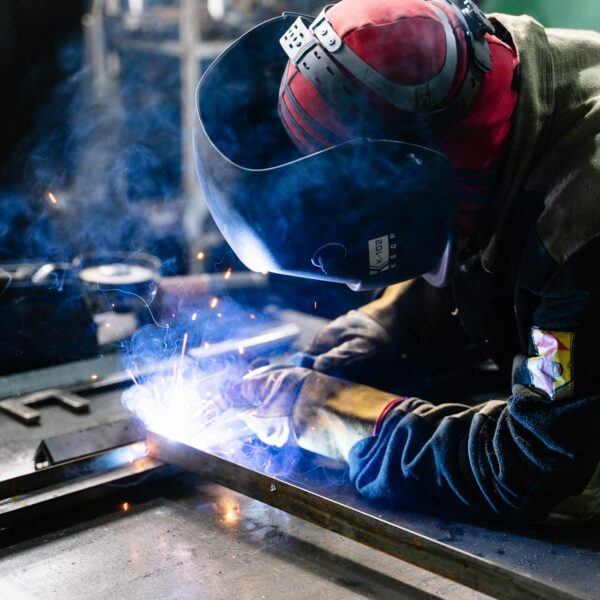 A person wearing PPE welding metal
