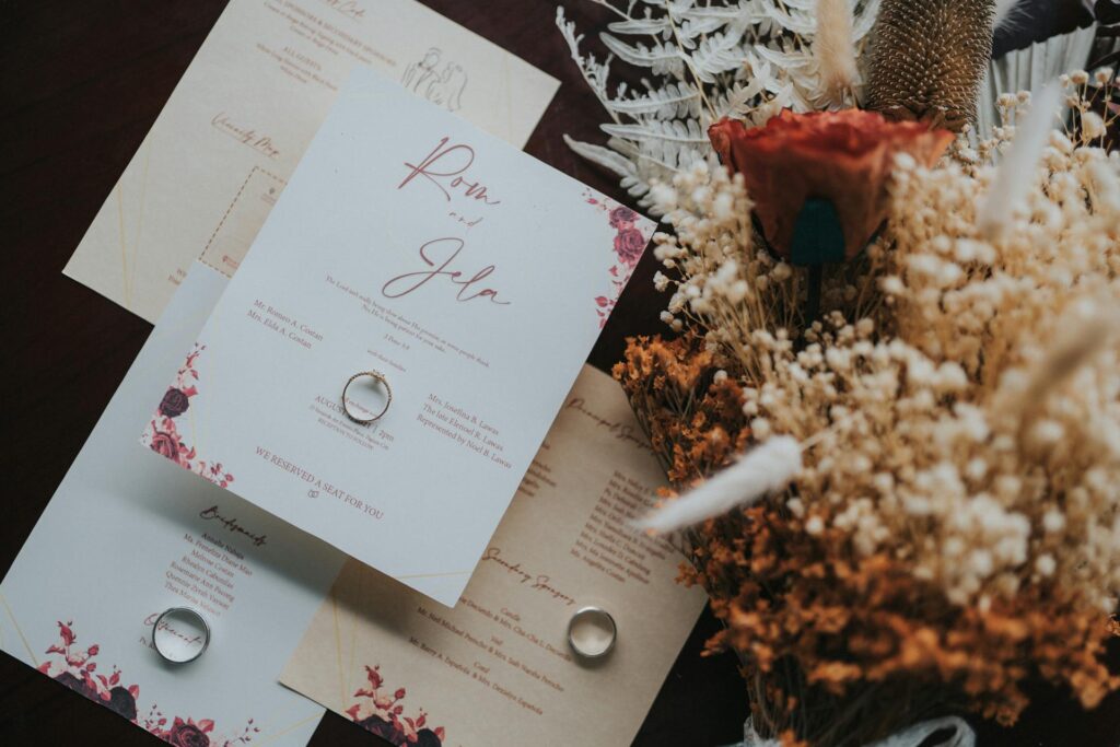 Wedding invitations on a table with wedding rings and a bouquet