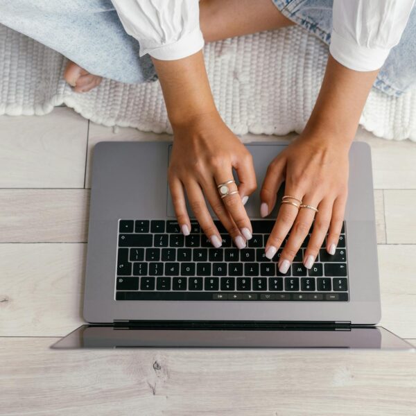 Person sitting on a rug and typing on a laptop